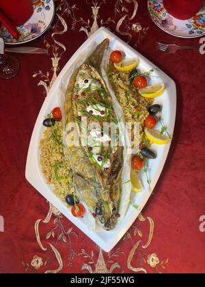 Piatti di pesce al forno con un contorno su un piatto bianco vista dall'alto Foto Stock