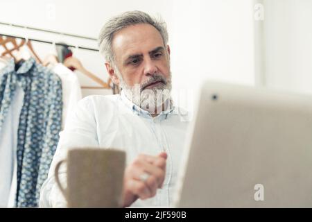 il maschio caucasico medio invecchiato guarda lo schermo dello spazio di copia del laptop home background concetto di lavoro remoto . Foto di alta qualità Foto Stock