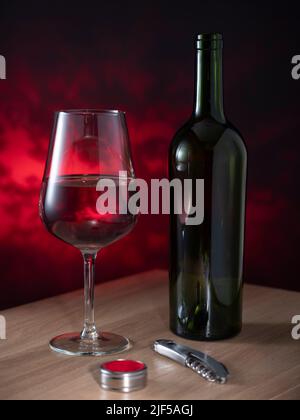 Helsinki / Finlandia - 26 GIUGNO 2022: Una bottiglia di vino rosso, un bicchiere e un cavatappi su sfondo scuro Foto Stock
