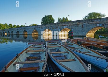 Noleggio di barche a remi di un giorno ormeggiate sul fiume Avon a Stratford upon Avon, con Clopton Bridge sullo sfondo. Foto Stock