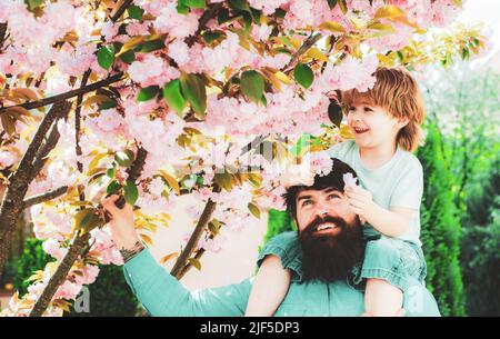 Buon giorno dei padri. Il padre che dà il figlio ride sul retro nel parco. Concetto di infanzia felice. Foto Stock