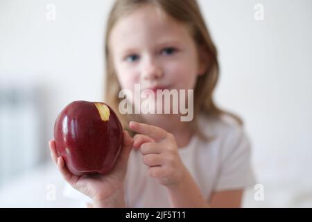 Ragazza bambino morde e mangia grande mela rossa Foto Stock