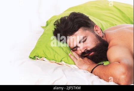 Bell'uomo a letto. Uomo bearded che dormiva sul letto in camera da letto. Buongiorno. Un giovane dormiva in letto con cuscini a casa. Foto Stock