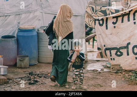 Bekaa, Libano. 3rd Dic 2021. Una madre siriana con i suoi due figli sta tornando a casa dal mercato. Una mattina in un campo profughi nella valle di Bekaa vivono circa 20 famiglie. Alcune famiglie attendono da cinque anni di andare in un altro luogo. Anche se la situazione permettesse loro di tornare in Siria, la maggior parte di loro solo canÃ-t.. I bambini nati in Libano non hanno un passaporto siriano, ma sono registrati nel paese. Pertanto i genitori soggiornano anche nel paese. Molti genitori hanno anche il loro permesso di soggiorno scaduto e non possono permettersi di avere un nuovo rilasciato, come molti vivono su tw Foto Stock