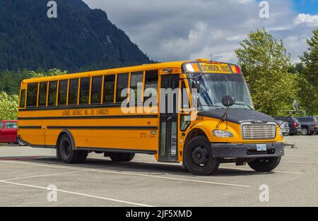 Scuola bus sul parcheggio su sfondo soleggiato. Bus scuola giallo. Foto di strada, nessuno, fuoco selettivo-Giugno 22,2022-Langley BC Canada Foto Stock