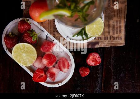 Acqua d'estate infusa con limone, lime, menta e ghiaccio di fragola. Rinfrescando, dieta, disintossicare l'acqua fortificata naturale. Seltzer duro con nootropics. Cocktail naturali sani. Bevande estive. Foto Stock