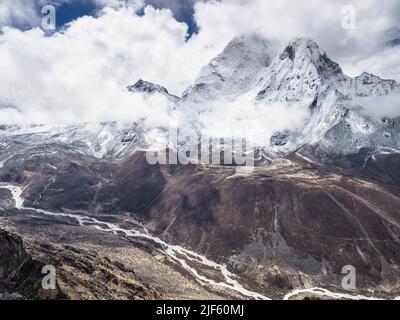 Faccia ovest di ama Dablam (6856m) circondato dalle nuvole di maggio sopra l'Imja Khola dalla cresta che conduce al picco di Nangkartshang sopra Dingboche. Foto Stock