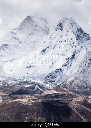 Faccia ovest di ama Dablam (6856m) circondata da nubi di maggio sopra l'Imja Khola visto dalla cresta che conduce al picco di Nangkartshang sopra Dingboche. Foto Stock