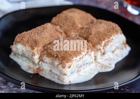 Baklava freddo. Baklava con latte su sfondo colorato. Specialità della cucina turca. Primo piano Foto Stock