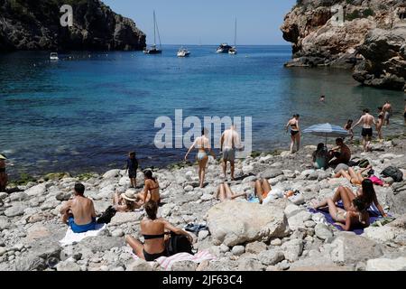 Deia, Spagna. 29th giugno 2022. I turisti prendono il sole e nuotano presso la spiaggia rocciosa Cala Deia di Maiorca. Credit: Clara Margais/dpa/Alamy Live News Foto Stock