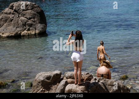 Deia, Spagna. 29th giugno 2022. I turisti prendono il sole e nuotano presso la spiaggia rocciosa Cala Deia di Maiorca. Credit: Clara Margais/dpa/Alamy Live News Foto Stock