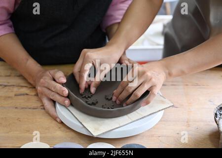 Vista croppata di donna anziana e giovane che decora la ceramica in officina. Artigianato, concetto hobby Foto Stock