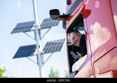 Medenbach, Germania. 30th giugno 2022. Un conducente di camion guarda fuori dal suo camion alla fermata di riposo Medenbach sul A3. Nell'ambito di un progetto pilota, gli spazi di parcheggio gratuiti per i veicoli industriali vengono ora registrati dai sensori e trasmessi ai conducenti tramite APP. Ciò ha lo scopo di semplificare la ricerca di posti di parcheggio gratuiti. Credit: Boris Roessler/dpa/Alamy Live News Foto Stock