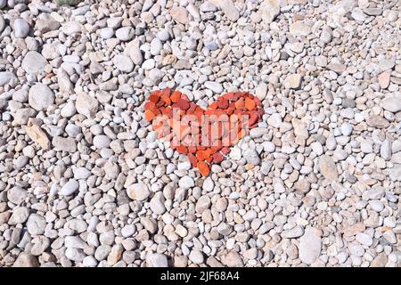 Forma a cuore rosso fatta di pietre e ciottoli da spiaggia. San Valentino simbolo. Foto Stock