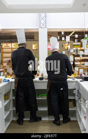 Due Chef visti da dietro: Servire i clienti dietro il loro tavolo. Foto Stock