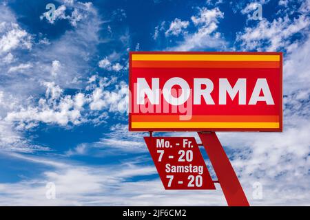 AUGSBURG, GERMANIA – 16 GIUGNO 2022: Segno pubblicitario del negozio discounter NORMA di fronte a un cielo con le nuvole Foto Stock