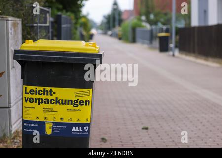 Lipsia, Germania. 30th giugno 2022. Un cosiddetto rifiuti giallo può per rifiuti di plastica leggera come l'imballaggio si trova su una piccola strada in una tenuta di alloggiamento in un giorno di svuotamento. L'Istituto dell'economia tedesca (Institut der deutschen Wirtschaft) ha calcolato, per l'associazione dei proprietari di immobili Haus und Grund, che esiste un divario significativo tra le spese di smaltimento dei rifiuti nelle principali città tedesche. Credit: Jan Woitas/dpa/ZB/dpa/Alamy Live News Foto Stock