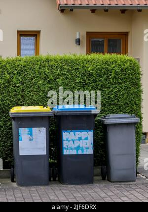 Lipsia, Germania. 30th giugno 2022. Una spazzatura rifiuti può per rifiuti residui, una spazzatura blu può per cartone e carta, e una spazzatura gialla può per rifiuti di plastica leggera come il supporto di imballaggio di fronte a due case semi-staccate. L'Istituto dell'economia tedesca (Institut der deutschen Wirtschaft) ha calcolato, per l'associazione dei proprietari Haus und Grund, che esiste un divario significativo tra le spese di smaltimento dei rifiuti nelle principali città tedesche. Credit: Jan Woitas/dpa/Alamy Live News Foto Stock