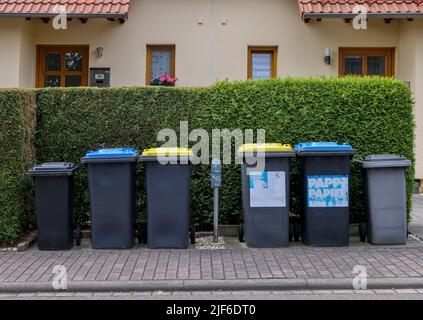 Lipsia, Germania. 30th giugno 2022. Bidoni neri per rifiuti residui, bidoni blu per rifiuti di cartone e carta, e bidoni gialli per rifiuti di plastica leggera come il supporto di imballaggio di fronte a due case semi-distaccate. L'Istituto dell'economia tedesca (Institut der deutschen Wirtschaft) ha calcolato, per l'associazione dei proprietari Haus und Grund, che esiste un divario significativo tra le spese di smaltimento dei rifiuti nelle principali città tedesche. Credit: Jan Woitas/dpa/Alamy Live News Foto Stock