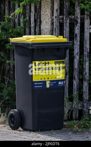 Lipsia, Germania. 30th giugno 2022. Un cosiddetto rifiuti giallo può per rifiuti di plastica leggera come l'imballaggio si trova su una piccola strada in una tenuta di alloggiamento in un giorno di svuotamento. L'Istituto dell'economia tedesca (Institut der deutschen Wirtschaft) ha calcolato, per l'associazione dei proprietari di immobili Haus und Grund, che esiste un divario significativo tra le spese di smaltimento dei rifiuti nelle principali città tedesche. Credit: Jan Woitas/dpa/Alamy Live News Foto Stock