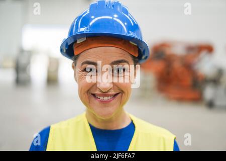 Donna ingegnere senior che lavora all'interno di una fabbrica robotica - Focus on Eyes Foto Stock