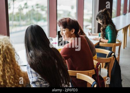 Giovane gruppo di studenti multirazziale che studia all'interno della biblioteca universitaria - Focus on asian man face Foto Stock