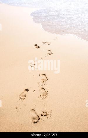 Impronte nella sabbia, essendo cancellati dalle onde Foto Stock