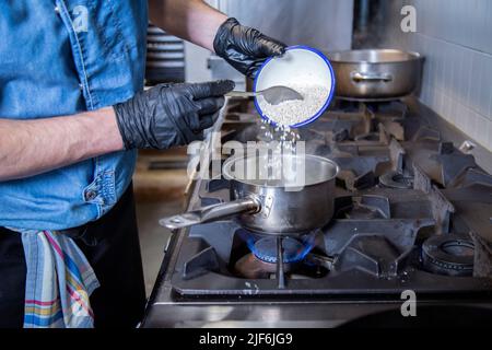 Comodo divano con poltrone e tavolino da caffè in vetro posto su tappeto grigio in spazioso soggiorno luminoso con camino e piante in vaso Foto Stock