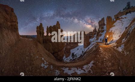 Silhouette di esploratore irriconoscibile in piedi con torcia sul paesaggio di formazioni rocciose in montagne innevate sotto il cielo stellato via lattiginosa in Goblin Foto Stock