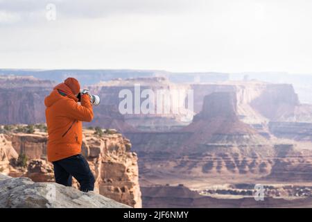 Fotografo irriconoscibile con fotocamera professionale che cattura paesaggi mozzafiato di formazioni rocciose negli altopiani del Canyonlands National Par Foto Stock