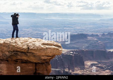 Fotografo irriconoscibile con fotocamera professionale che cattura paesaggi mozzafiato di formazioni rocciose negli altopiani del Canyonlands National Par Foto Stock