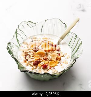 Ciotola con yogurt e cereali per la colazione con un cucchiaio di metallo su un tavolo Foto Stock