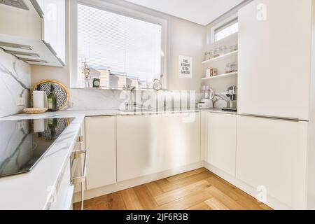 Frammento di interno di piccola cucina domestica con stile minimalista mobili bianchi con lavandino e stufa Foto Stock