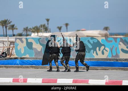 Khan Yunis, territori palestinesi. 30th giugno 2022. I membri armati delle forze di sicurezza palestinesi di Hamas prendono parte a un trivellazione in occasione di una cerimonia pubblica di laurea per gli ufficiali di polizia, durante la quale i cadetti mostrano le loro capacità militari. Hamas sta intensificando i corsi militari per i suoi poliziotti per prepararli a potenziali scontri con le forze israeliane. Credit: Mohammed Talatene/dpa/Alamy Live News Foto Stock