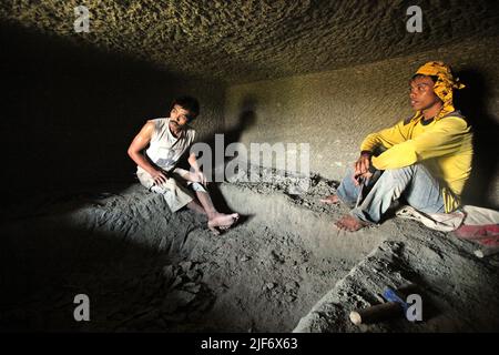 I lavoratori sono fotografati mentre stanno riposando dallo scavo e dal carving attraverso la roccia per costruire una camera per la tomba tradizionale della camera di pietra a Toraja del nord, Sulawesi del sud, Indonesia. Foto Stock