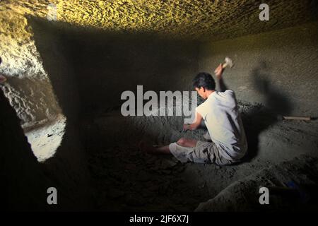 Un operaio sta scavando e scavando attraverso la roccia per costruire una camera per la tradizionale tomba a camera di pietra a Toraja Nord, Sulawesi Sud, Indonesia. Foto Stock