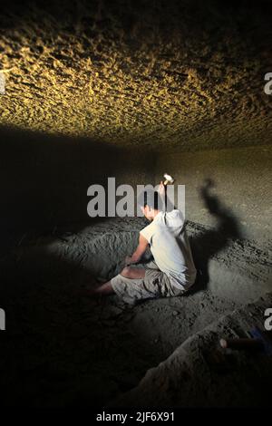 Un operaio sta scavando e scavando attraverso la roccia per costruire una camera per la tradizionale tomba a camera di pietra a Toraja Nord, Sulawesi Sud, Indonesia. Foto Stock