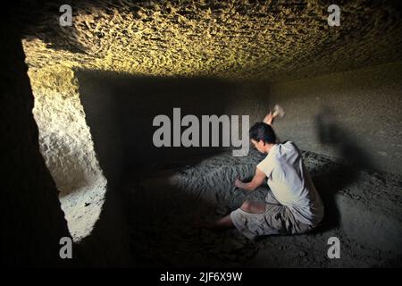 Un operaio sta scavando e scavando attraverso la roccia per costruire una camera per la tradizionale tomba a camera di pietra a Toraja Nord, Sulawesi Sud, Indonesia. Foto Stock