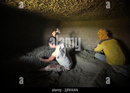 Operai che scavano e intagliano attraverso la roccia per costruire una camera per la tomba tradizionale camera di pietra a Nord Toraja, Sulawesi Sud, Indonesia. Foto Stock