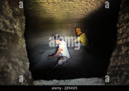 Operai che scavano e intagliano attraverso la roccia per costruire una camera per la tomba tradizionale camera di pietra a Nord Toraja, Sulawesi Sud, Indonesia. Foto Stock