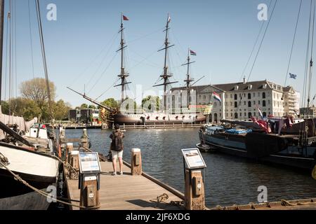 Un turista scatta una foto di una replica di una Vereenigde Oostindische compagnie, olandese compagnia dell'India orientale, nave, l'Amsterdam, ormeggiata fuori Het Scheepvaartmuseum, il Museo Marittimo Nazionale di Amsterdam, Paesi Bassi. Foto Stock