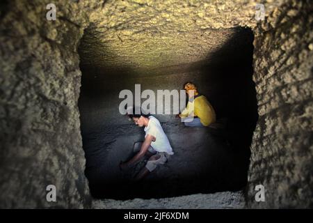 Operai che scavano e intagliano attraverso la roccia per costruire una camera per la tomba tradizionale camera di pietra a Nord Toraja, Sulawesi Sud, Indonesia. Foto Stock