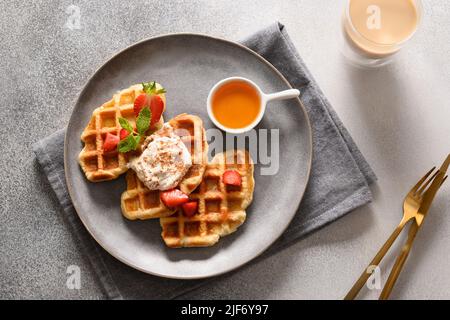Colazione alla moda con crostini e caffè del mattino, fragole su sfondo grigio. Croissant come waffle. Vista dall'alto. Foto Stock