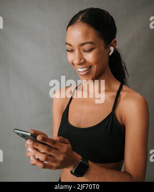 Primo piano la donna afroamericana che tiene il suo cellulare nelle sue mani Foto Stock