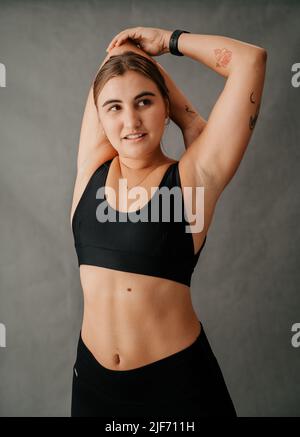 Giovane donna caucasica facendo esercizi di allungamento del braccio Foto Stock