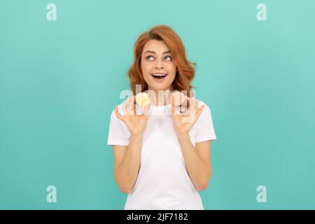 la ragazza stupita tiene dolce biscotto francese macaron su sfondo blu Foto Stock