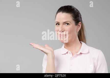 la donna di mezza età mostra un gesto di presentazione Foto Stock