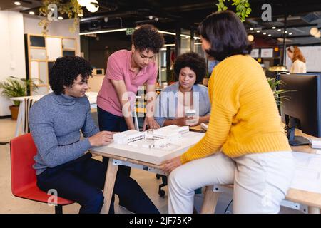 Architetti multirazziali maschili e femminili che discutono sul modello architettonico in ufficio Foto Stock