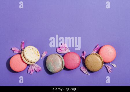Macaron con petali di fiore di peonie su sfondo molto peri colore. Dolce dessert, colori pastello e colorati caramelle, concetto estivo. Stile romantico, fe Foto Stock