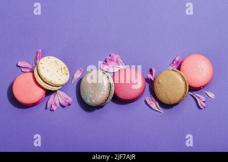 Macaron con petali di fiore di peonie su sfondo molto peri colore. Dolce dessert, colori pastello e colorati caramelle, concetto estivo. Stile romantico, fe Foto Stock
